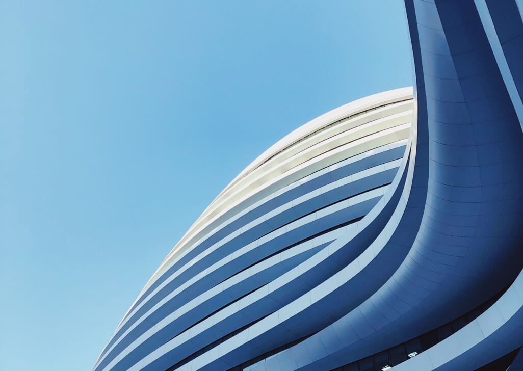 Curved side of a modern building looking up to a clear blue sky